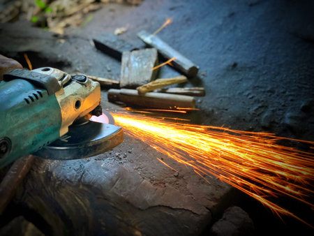 Worker cutting steel with electric grinder. Sparks while grinding iron