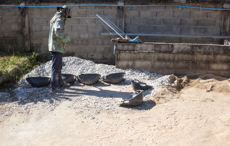Worker use hoe to collect gravel into the basket.のeditorial素材