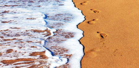 The coast, clear water with beautiful shallow waves and white foam washes the coast with smooth...