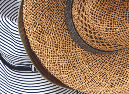 Summer round hats - braided brown hat and striped white and blue fabric hat - sold in the store, close-upの写真素材