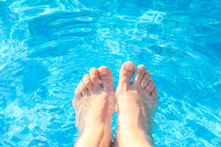 Feet of bare feet in blue water close-upの写真素材