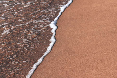 Close-up of the sea coast, clear sea water washes the shore with a brown sandの写真素材