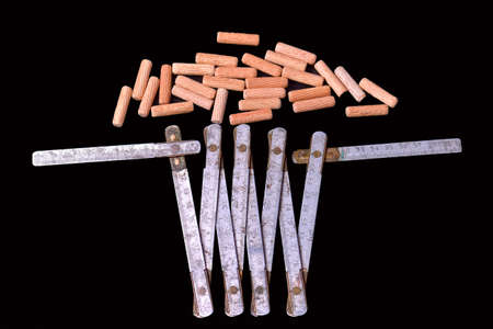 Wooden dowel pins and folding meter on black backgroundの写真素材