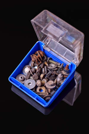 Blue box with old rusty bolts, screws, brackets, various metal details on black backgroundの写真素材