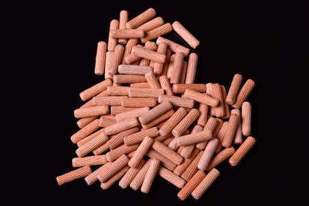 Close up heap of wooden dowel pins on black backgroundの写真素材