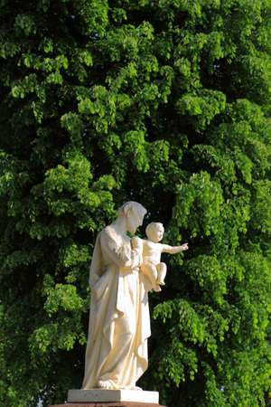 White Statue Against Green Leavesの写真素材
