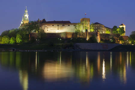 Poland, Krakow, Wawel Royal Castle Lit-up, spring, evening, seen from the west, national flag flyingの写真素材