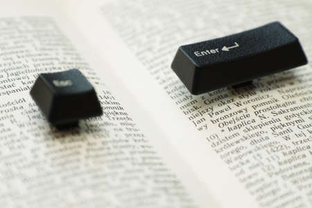 Enter and escape computer keys placed on a paper book spread, close upの写真素材