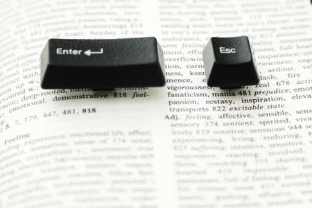 Enter and escape computer keys placed on a paper book spread, close upの写真素材