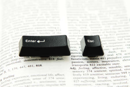 Enter and escape computer keys placed on a paper book spread, close upの写真素材