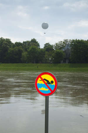 Poland, KrakÃ³w, flooded Vistula/WisÅa river embankments, no swimming sign over the water, sightseeing baloon in the backgroundの写真素材