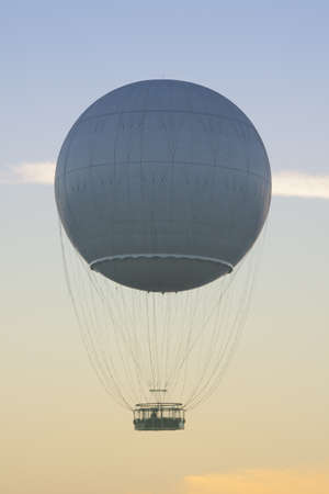 Helium balloon seen against colorful sky at dusk, jest-trail visible in the backgroundの写真素材
