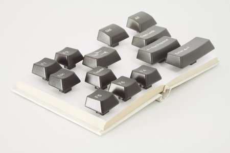 Various computer keys placed on a small book spread, white backgroundの写真素材