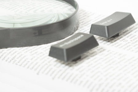Enter and Backspace Computer Keys and a magnifying glass placed on a book page