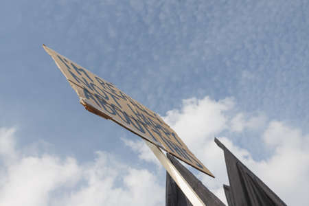 Cardboard hand made banner and tops of black flags against blue cloudy skyの写真素材