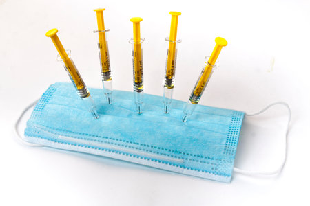 Vaccination syringes piercing a mask as a symbol of supressing the pandemic