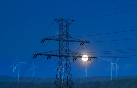 View of a high voltage line pylon, dark sky and moon in the background, symbolic image of power price crisis, wind turbines in the distance as a possible solutionの写真素材
