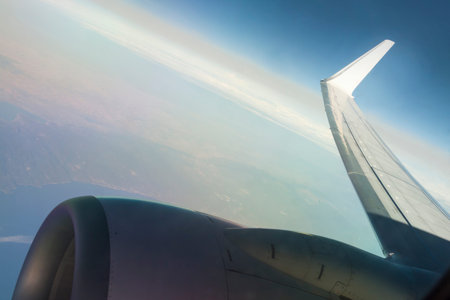 Jet Engine and Wing of an Aircraft in Flight, sunlit, sky and landscape seen from above