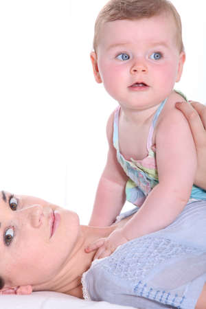 Mother playing with her baby girl on her chestの写真素材