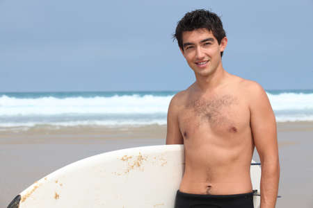 Young man at the beach with surfboardの写真素材