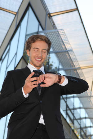 Man checking his watch against his cellphoneの写真素材