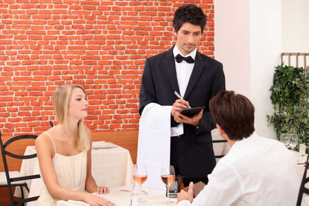 Couple being served by a waiterの写真素材