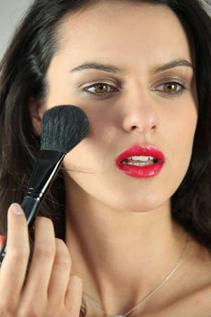 Woman applying blush on her cheeksの写真素材