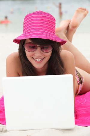 Brunette teenager at the beach with laptop computerの写真素材