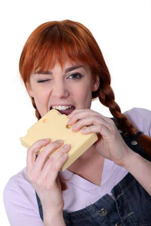 Woman biting into block of cheeseの写真素材