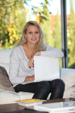 Blond girl sat at home with laptop computerの写真素材