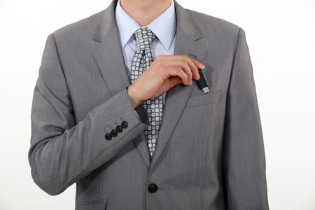 A businessman putting his Usb key in his pocket.
