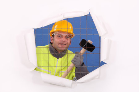 A man with a sledgehammer behind a wire netting.