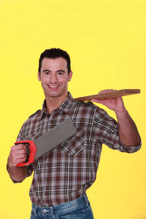 A carpenter carrying a plank and a handsaw.の写真素材
