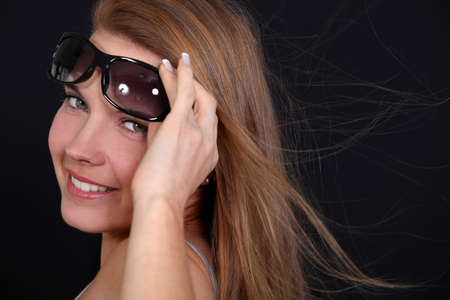 Woman wearing sunglasses on a breezy dayの写真素材