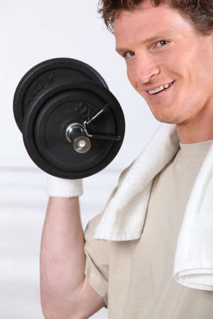Smiling man lifting barbell on white backgroundの写真素材