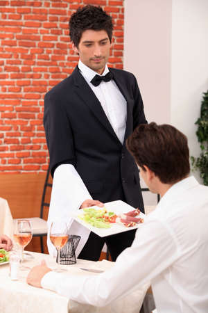 Waiter serving a meal in a restaurantの写真素材