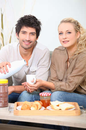 Couple eating breakfast on a sofaの写真素材
