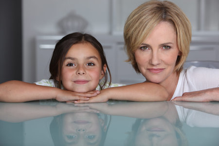 Woman and young girl leaning on glass surface