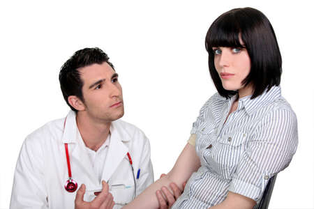Doctor kneeling by a female patientの写真素材