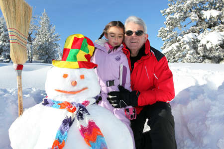 Father and daughter building snowman togetherの写真素材
