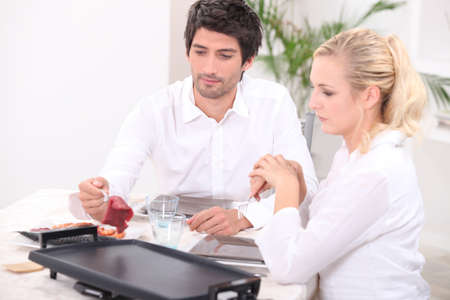 Couple cooking meat on hotplateの写真素材