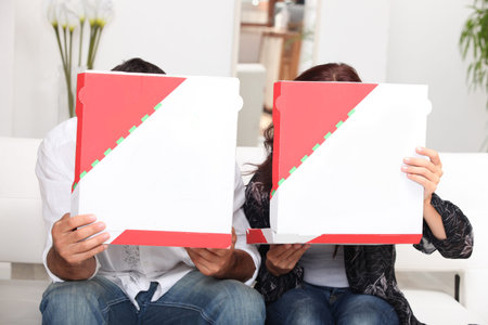 couple hiding behind pizza boxes