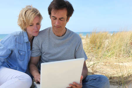Couple on laptop at the beachの写真素材