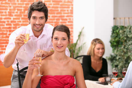 Couple holding champagne flutes in restaurantの写真素材