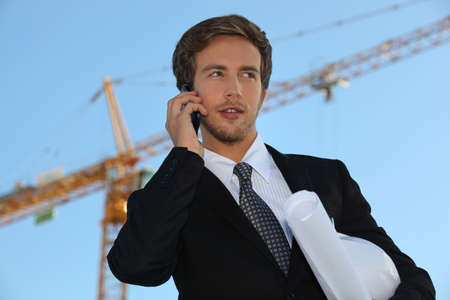 Architect on site with plans and cellphoneの写真素材