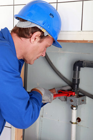 Man installing water pipes with a large wrench