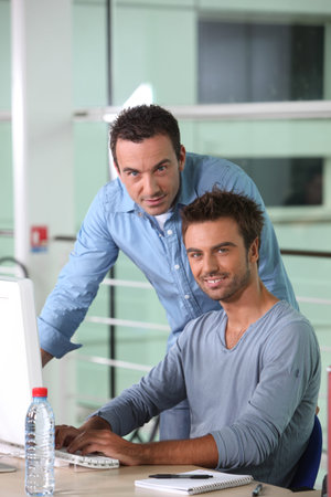 Two men working at a desktop computer