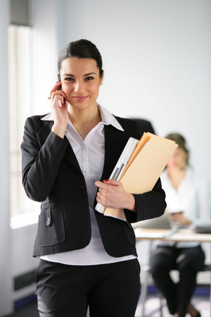 Brunette holding folders and mobile telephone