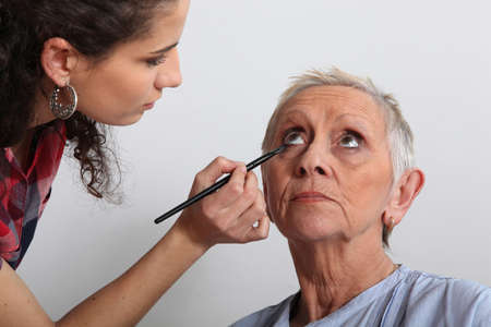Woman applying makeup to an older ladyの写真素材