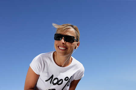 Woman in sunglasses listening to music through headphonesの写真素材